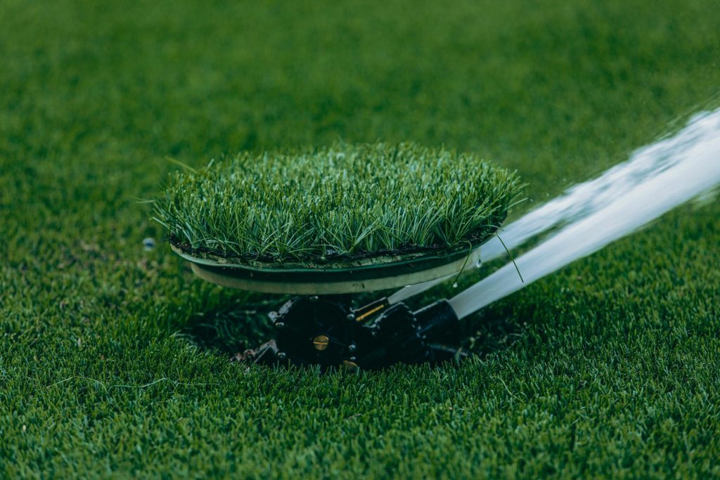Close-up of an automatic sprinkler watering a lush green lawn, showcasing irrigation system.